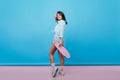 Full-length portrait of ecstatic asian girl looking over shoulder while posing with skateboard. Indoor photo of slim Royalty Free Stock Photo