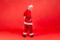 Full length portrait of elderly man with gray beard in santa claus costume standing backwards with Royalty Free Stock Photo