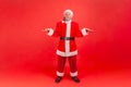 Full length portrait of elderly man with gray beard wearing santa claus costume shrugging