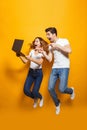 Full length portrait of excited man and woman jumping and using Royalty Free Stock Photo