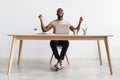 Excited young black man gesturing YES in front of laptop, celebrating success or achievement, sitting at desk in office Royalty Free Stock Photo