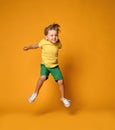 Full length portrait of an excited young boy jumping leaping in green shorts over yellow Royalty Free Stock Photo