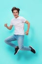 Full length portrait of an excited young man in white t-shirt jumping while celebrating success isolated over blue background Royalty Free Stock Photo