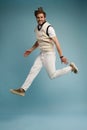 Full length portrait of an excited young man in white t-shirt jumping while celebrating success isolated over blue Royalty Free Stock Photo