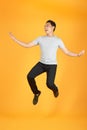 Full length portrait of an excited young man in white t-shirt jumping while celebrating success isolated over orange background Royalty Free Stock Photo