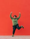 Full-length portrait of a fat dancer shows a performance against a red wall, looks at the camera and listens to music on Royalty Free Stock Photo