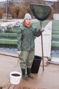 Full-length portrait of female with landing net on fish farm