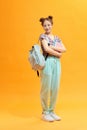 Full length portrait of a female student with a backpack and books isolated on yellow background Royalty Free Stock Photo