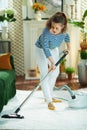 Focused modern housewife vacuuming white fluffy carpet