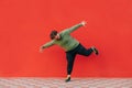 Full-length portrait of a funny fat man dancing on a red background, wearing casual clothes, looking at the camera and smiling Royalty Free Stock Photo