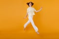 Full-length portrait of glad girl in yellow t-shirt and white pants running on orange background. Studio shot of Royalty Free Stock Photo