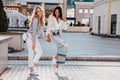 Full-length portrait of good-looking ladies dancing with happy smile. Outdoor photo of well-dressed friends walking