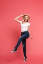 Full length portrait of gorgeous blond woman 20s wearing casual jeans and straw hat smiling and walking Royalty Free Stock Photo