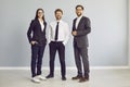 Three cheerful business people standing isolated on grey background and looking at camera. Royalty Free Stock Photo