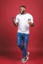 Full length portrait of handsome African American man with mobile phone and take away coffee cup. Isolated over red background Royalty Free Stock Photo