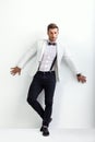 Full length portrait of handsome man in white elegant suit posing and leaning at wall Royalty Free Stock Photo