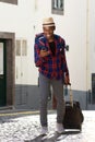 Full length happy african american travel man walking with bags and cellphone on street Royalty Free Stock Photo