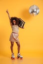 Full length portrait of happy afro american disco woman in sunglasses pointing with finger upward, standing on roller Royalty Free Stock Photo