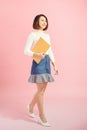 Full length portrait of a happy asian businesswoman holding document while walking isolated over pink background Royalty Free Stock Photo