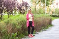 Full length portrait of happy beautiful young successful blogger businesswoman in elegance style standing on green park, holding