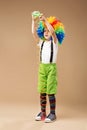 Full-length portrait of Happy clown boy with large colorful wig.