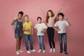 Full length portrait of happy diverse schoolkids making different gestures on pink background