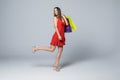 Full length portrait of a happy excited woman in red dress standing and holding colorful shopping bags on a white background Royalty Free Stock Photo