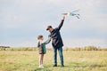 Full length portrait of happy family father and child daughter launch a kite on meadow, wearing coats, spending day off in active Royalty Free Stock Photo