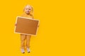 Full length portrait of happy little girl with empty cork board on yellow background. Copy space, mock up Royalty Free Stock Photo