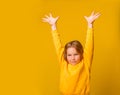 Full length portrait of happy little girl in yellow clothes standing with hands raised up isolated on yellow background Royalty Free Stock Photo