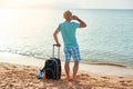 Full length portrait of happy man with suitcase and mobile phone standing on beach freelancer on a sunny day on vacation Royalty Free Stock Photo