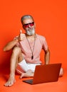 Full length portrait of a happy old man using laptop computer isolated over orange background Royalty Free Stock Photo