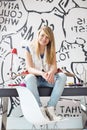 Full-length portrait of happy teenage girl with skateboard sitting on study table at home Royalty Free Stock Photo