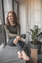 Unconcerned girl sitting on windowsill expecting someone with joy Royalty Free Stock Photo