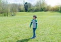 Full length Portrait Happy young boy standing in the park with blurry grass fields and  trees background,Active child looking out Royalty Free Stock Photo