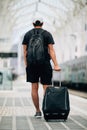 Full length portrait of a happy young man walking with suitcase at train station. Travel concept Royalty Free Stock Photo