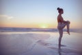 Healthy woman jogger at beach at sundown stretching