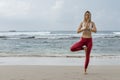 Full length portrait of healthy young woman doing yoga balance exercise at the beach. Copy space Royalty Free Stock Photo