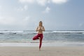 Full length portrait of healthy young woman doing yoga balance exercise at the beach Royalty Free Stock Photo