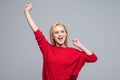 Full length portrait of a joyful blonde young woman jumping and celebrating over gray background Royalty Free Stock Photo