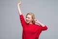 Full length portrait of a joyful blonde young woman jumping and celebrating over gray background Royalty Free Stock Photo