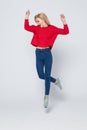 Full length portrait of a joyful young woman jumping and celebrating over gray background Royalty Free Stock Photo