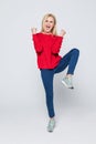 Full length portrait of a joyful young woman jumping and celebrating over gray background Royalty Free Stock Photo