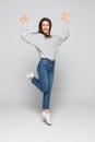 Full length portrait of a joyful young woman jumping and celebrating over gray background Royalty Free Stock Photo