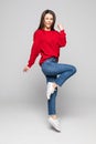 Full length portrait of a laughing woman in red sweater jumping over gray background Royalty Free Stock Photo