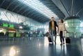 Full-length portrait of a loving couple travelling together, man and woman with suitcases walking along the departure hall of Royalty Free Stock Photo