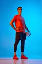 Full-length portrait of male volleyball player posing with ball  on blue studio background in neon light. Sport Royalty Free Stock Photo