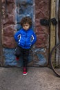 Full length portrait of an mixed race little boy standing on a dirty city street