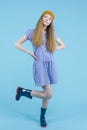 Full Length Portrait of Moving Caucasian Teenage Girl In Long Blue Dress, Wellington Rubber Boots Posing In Winter hat Against Royalty Free Stock Photo