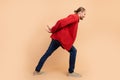 Full length portrait of nice young man arms carry empty space wear red shirt on beige color background